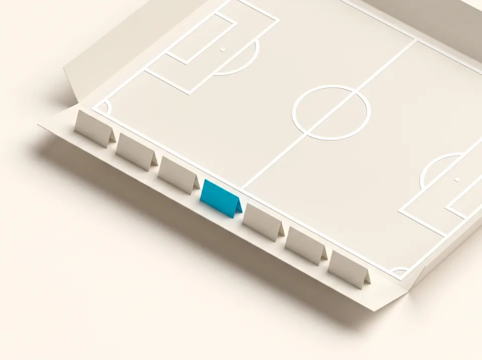 Papier-Illustration: ein Sportplatz aus Faltpapier mit Linienmarkierungen und Aufstellungskarten am Rand, eine Karte in Cyan